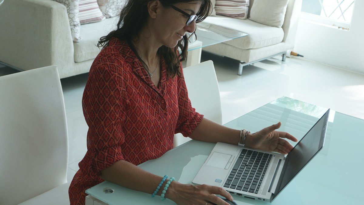 Femme travaillant sur son ordinateur portable à une table dans son salon