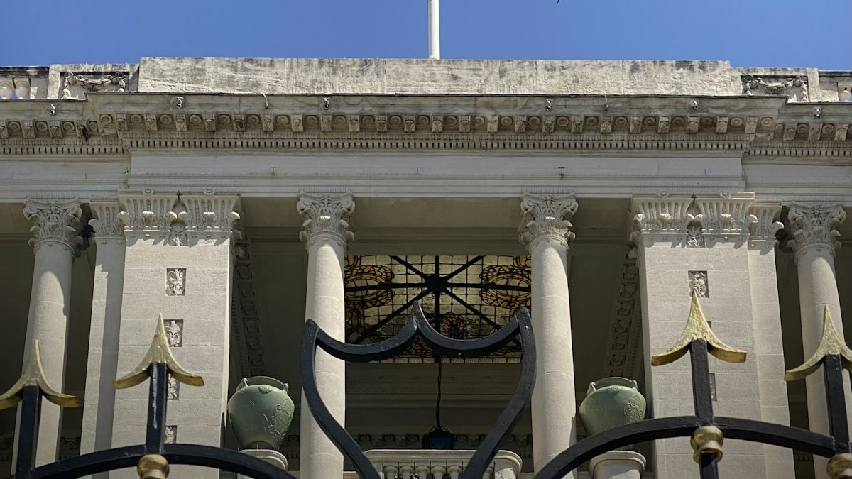 Façade à colonnes d'un bâtiment public derrière une grille en fer forgé