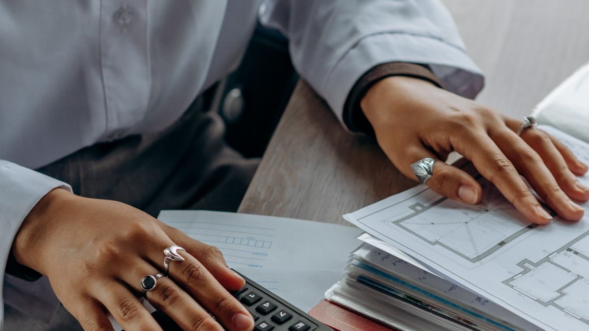 Mains sur une calculatrice à côté d'une pile de documents