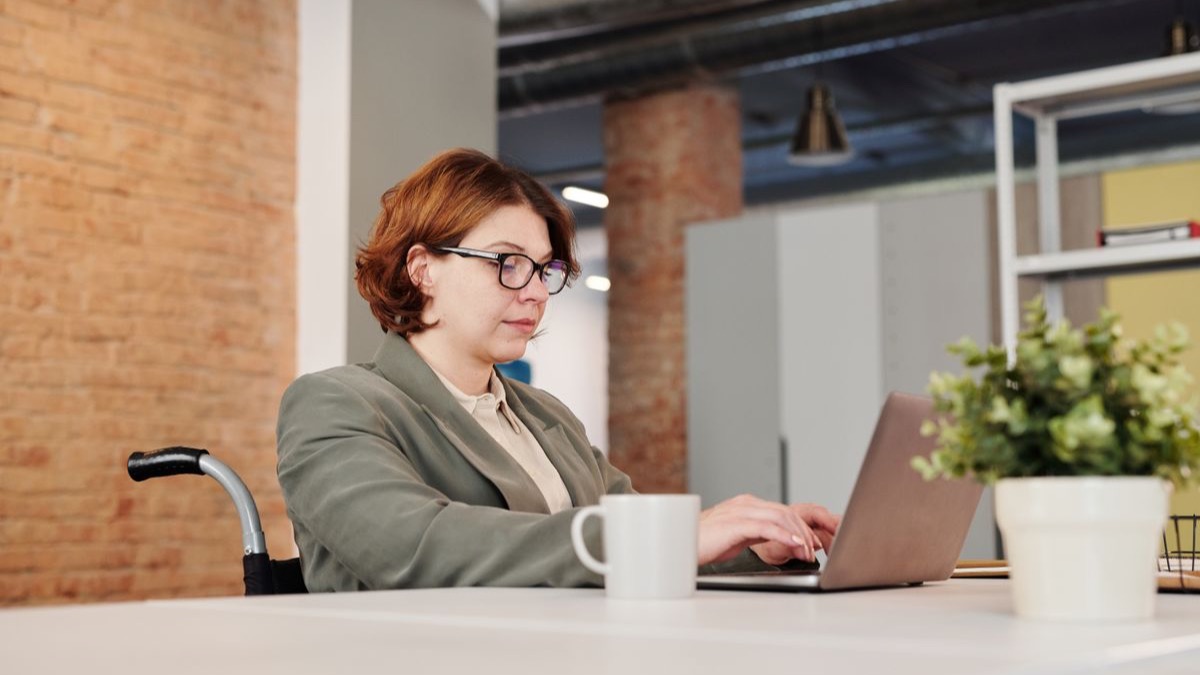 Femme en fauteuil roulant travaillant sur son ordinateur portable au bureau