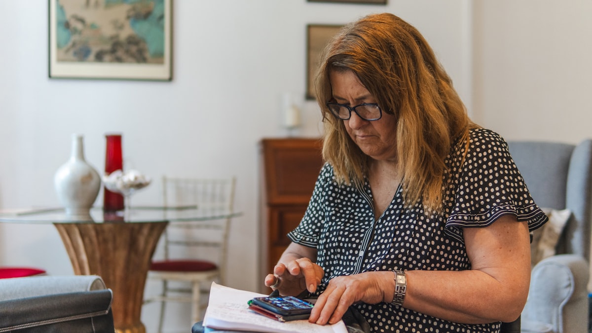 Retraitée vérifiant ses relevés de pension avec une calculatrice