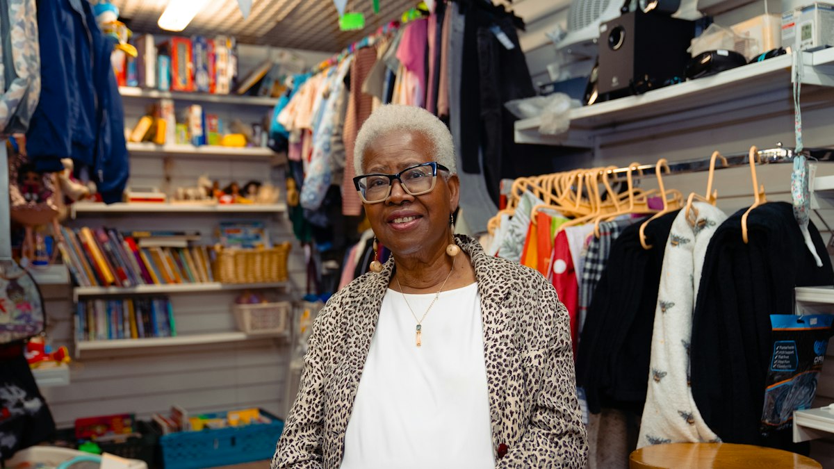 Commerçante senior souriante dans sa boutique de vêtements et de jouets